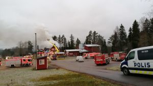 Fortfarande när det ljusnar stiger det rök från skolan. Släckningsarbete pågår vid en skola.
