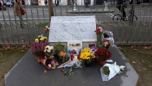 Vid minnesstenen för de dödade på Bataclan läggs blommor inför den 13 november. Ljus och blommor vid en grå minnessten.