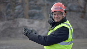 Mika Wiljanen, vd för St1, visar vilket område som ska röjas för bränsleterminalen och kajen. Mika Wiljanen pekar mot ett berg.