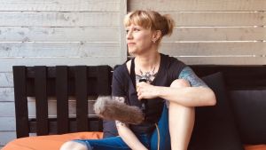 Pauliina Motturi Dokumentaristi Pauliina Motturi istuu sängyllä mikrofonin kanssa.