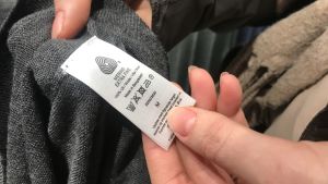 Kvaliteten på kläderna varierar och det finns så många olika materialblandningar i textilierna, vilket gör insamlingen, sorteringen och återvinningen svårare. en klädlapp på ett klädesplagg som någon håller i