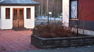 Gården har stenbeläggning och gräs. Terrass och gård med stenplattor och lusthus.