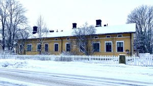 Kotka Svenska Barnträdgårds anrika trähus väntar på att renoveras. Ett gult trähus i vintrig stadsbild.