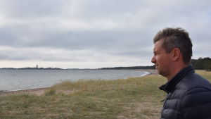 Björn Peltonen är ny ordförande för Hangö miljönämnd. Man klädd i mörkblå jacka blickar ut över en strand.