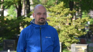 Historikern Matias Kaihovirta bor i Karis. Man klädd i blått står på en begravningsplats.