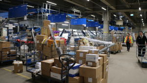 Mathias Rosenlund jobbar på Matkahuoltos logistikcentral Inne i en logistikcentral med stora mängder paket framför rullband.