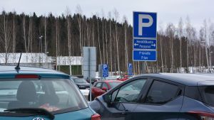 Bilar på en parkeringsplats. På en skylt står det att platserna närmast kameran är till för personal.