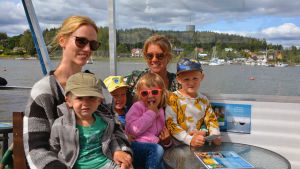 Från vänster: Karoliina Klavér med sonen Einar, 2 år. Edwin Tukiainen, 5 år, mamma Karolina Nyman med dottern Fanny Tukiainen, 4, i famnen. Emil klavér, 5 år. En familj med två vuxna och fyra barn sitter i ett kryssningsfartyg.