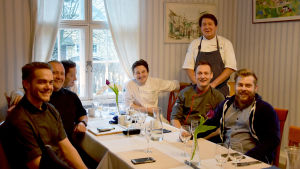 På bilden är nästan alla föreningens medlemmar samlade. Från vänster sitter Samuel Mikander, Kenneth Löfberg, "Weccu" Weckström, Niko Tuominen, Hasse Lundström, Uffe Wadenström och Micke Kokkonen. En bild på sju män som har startat en förening för köksmästare. De sitter runt ett bord och ler mot kameran. I bakgrunden finns ett fönster.
