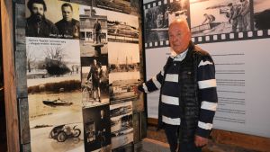 Torgils Bäckman har varit guide i Skärimuseet ända sedan det öppnade sommaren 2012. En man i svartvitrandig tröja står framför en vägg med fotografier.