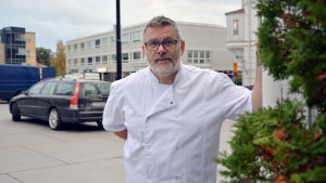 Kim Holmberg säger att det är färre kunder när parkeringen på torget är begränsad. Det lönar sig dock att ha ena kaféet öppet på söndagar. Kim Holmberg. I bakgrunden syns torget i Ekenäs.