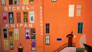 Omslaget till Sanna Manders barnbok Nyckelknipan får sina sista detaljer. En bild av ett orangefärgat hus i bilderboken Nyckelknipan.