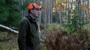 Magnus Nylander står snällt och väntar på att Choko ska komma tillbaka till honom. Magnus står bland granar och björkar och tittar mot skogen.