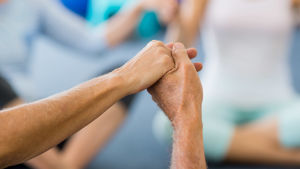 Dans kan lindra psykiska trauman. händer som håller i varandar. Det är händer på äldre mänskor. Kan tolkas som dans eller gruppgymnastik eller yoga.