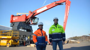 Inkoo Shippings tekniska chef, Jani Nordman och vd Thomas Bergman (i gult) framför den nya lyftkranen. Två mån i hjäl och neonfärgade (orange och gul) arbetskläder står framför en ny, stor lyftkran.