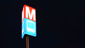 M-märket guidar den morgontrötte rätt till Mattby bussterminal. Metro- och bussmärket lyser i mörknet.