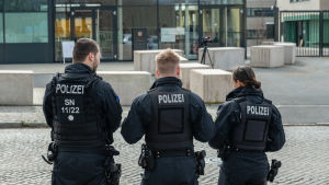 Tysk polis utanför rättegångsbyggnaden i Dresden i Tyskland den 18 mars 2019. Tre tyska poliser i uniform står med ryggen emot.