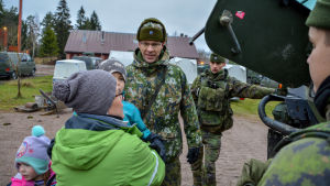 Mats Hansson svarar på frågor. Dagisbarn och soldater framför ett militärfordon.