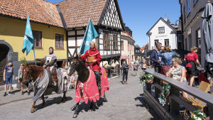 Coronariddarna på Gotland blev snabbt en världsnyhet och uppskattas av turisterna. Två riddare på häst rider igenom Visby med flaggor som uppmanar turisterna att hålla avstånd.