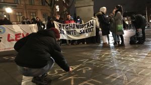 Under hösten demonstrerade unga afghaner för att få stanna i Sverige. Demonstration där en man skriver på gatan och i bakgrunden tiotal personer och plakat om att Afghanistan inte är säkert.
