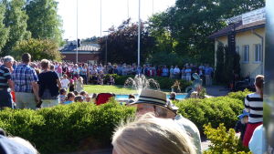 Det soliga vädret och Eurydike fick Karisborna att gå man ur huse En bild på många människor som har samlats runt en liten staty. De står i en park med grönt gräs och buskar.