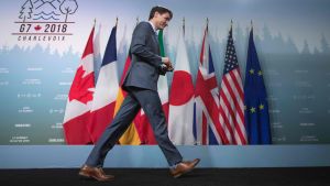 JustinTrudeau lämnar presskonferensen som retade upp Donald Trump. Justin Trudeau med långa steg på väg ut till höger framför flaggrad.