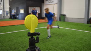 En fotbollsjunior springer och mätinstrumentet registrerar snabbheten. Futura-fotbollsspelare springer förbi en elektronisk avläsare