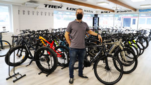 Aleksi Sanaksenaho säger att de redan måste göra beställningar för år 2022. Aleksi Sanaksenaho står framför en stor rad cyklar i en cykelaffär.