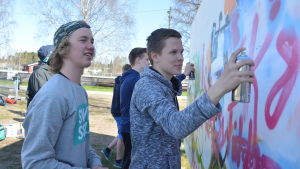 Eddi Bussman målar och Milton Holmqvist ser på. Eddi Bussman målar graffiti på Raseborg offspring 2016. Milton Holmqvist till vänster.
