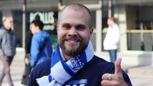 Rasmus Pinomaa håller på HJK i vått och torrt. Han är mycket aktiv inom Klubipääty. HJK-supportern Rasmus Pinomaa ler och visar tumme upp.