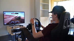Janne Lipponen besöker ofta den nya mopedverkstaden i Pyttis. Bild på Janne Lipponen som spelar rally i en simulator framför tv:n.