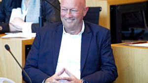 Thomas Kemmerich. Thomas Kemmerich sitter framför en mikrofon och ler. Han tittar åt sidan och sitter med händerna ihop.