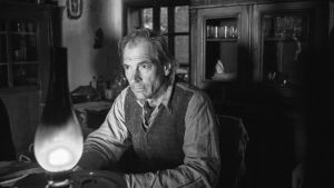 Skenbart ljust och varmt? Julian Sands spelar en av de människor som den lilla pojken möter. En man sitter i dunklet vid en fotogenlampa.