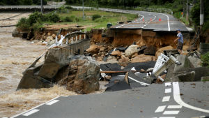 En man försöker korsa en kollapsad väg i Higashihiroshima i Japan. En man försöker korsa en kollapsad väg i Higashihiroshima i Japan.