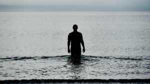 Christian (Simon Sears). Mörk bild av karaktären Christian som går ut i havet.