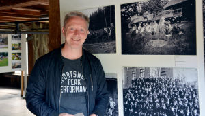 Historiker Kim Björklund föreläser om Billnäs bruks historia. De svartvita bilderna visar arbetare som jobbade i bruket förr. Historiker Kim Björklund står vid fyra svartvita bilder som visar arbetare i Billnäs bruk.