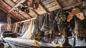 Förr gjorde man fiskenäten för hand, alla tusentals knutar. Granösundin saaristolaismuseon sisäpuolelta otettu kuva jossa näkyy vanha soutuvene ja kalaverkkoja.