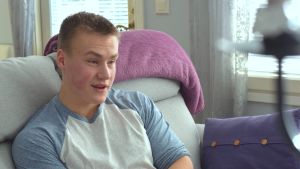 Robin Järviö, som nu är 19 år, behöver upp till tolv timmar sömn i dygnet för att klara av vardagen då sömnkvaliteten lider av narkolepsin. Han vaknar omkring tio gånger per natt. Robin Järviö sitter på en soffa framför ett fönster.