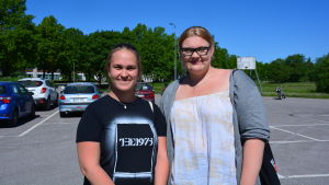 Gymnasieeleverna Esmeralda Laurén och Hanna Nyström. gymnasieeleverna esmeralda och hanna står på en parkeringsplats med klarblå bakgrund