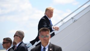 Donald Trump omgiven av livvakter går upp för trappan till sitt flygplan