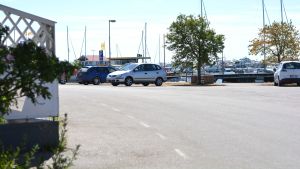 Området som skulle begränsas för trafik i Östra hamnen. Parkeringsplats med några bilar en varm sommardag. Hav och båtar i bakgrunden.