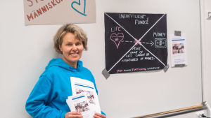 Läraren Lena Ray är stolt över sina studerande, som jobbar hårt med projektet. En glad kvinna står framför en tavla med plakat om människohandel.