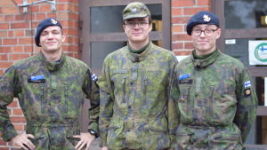 Beväringarna Max Kopra, Joar Cederberg och Robin Bucher. Tre beväringar i kamouflagemönstrad uniform. Står utanför en röd tegelbyggnad (Soldathemmet)
