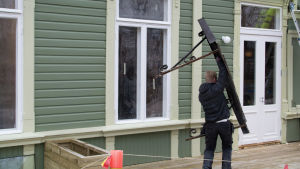 Här kommer de tillbaka, entrétaken som igen ska fästas ovanför dörrarna. bild på en man