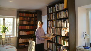 Ulla-Lena Lundberg tar ofta emot gäster i biblioteket. Här bläddrar hon i en av sina böcker om hällristningar. Ulla-Lena Lundberg i Diktarhemmet i Borgå.