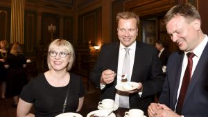 Försvarsminister Antti Kaikkonen, social- och hälsovårdsminister Aino-Kaisa Pekonen och utvecklings- och utrikeshandelsminister Ville Skinnari låter sig väl smaka under kaffebjudningen på Ständerhuset. Leende ministrar äter tårta.