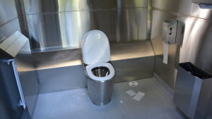 metall/plåtgrå insida i en av kuppisparkens nya toaletter. syns en toalettstol och wc-papper på sidan.