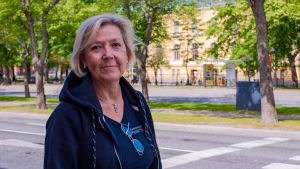 Monica Johnson. En kvinna utomhus, i bakgrunden en esplanad och ett gult stenhus.