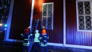 Gnistorna från lagerbyggnaden flög mot kyrkan och en av kyrkans fönsterposter hann fatta eld innan brandmännen var på plats. Brandmännen pekar på fönstret som nästan fattade eld.