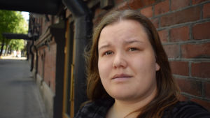 Jasmina Haverinen vill inte ha barn. En kvinna står framför en tegelvägg och tittar in i kameran.